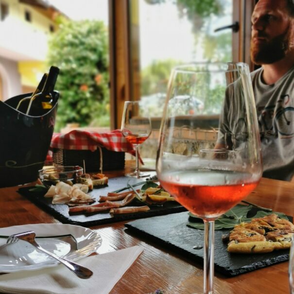 Glases of wine and local tapas on the table. A man is sitting and listening to the winemaker.